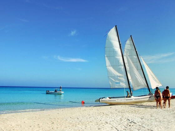 Sailboat on a tropical beach with people enjoying the shoreline